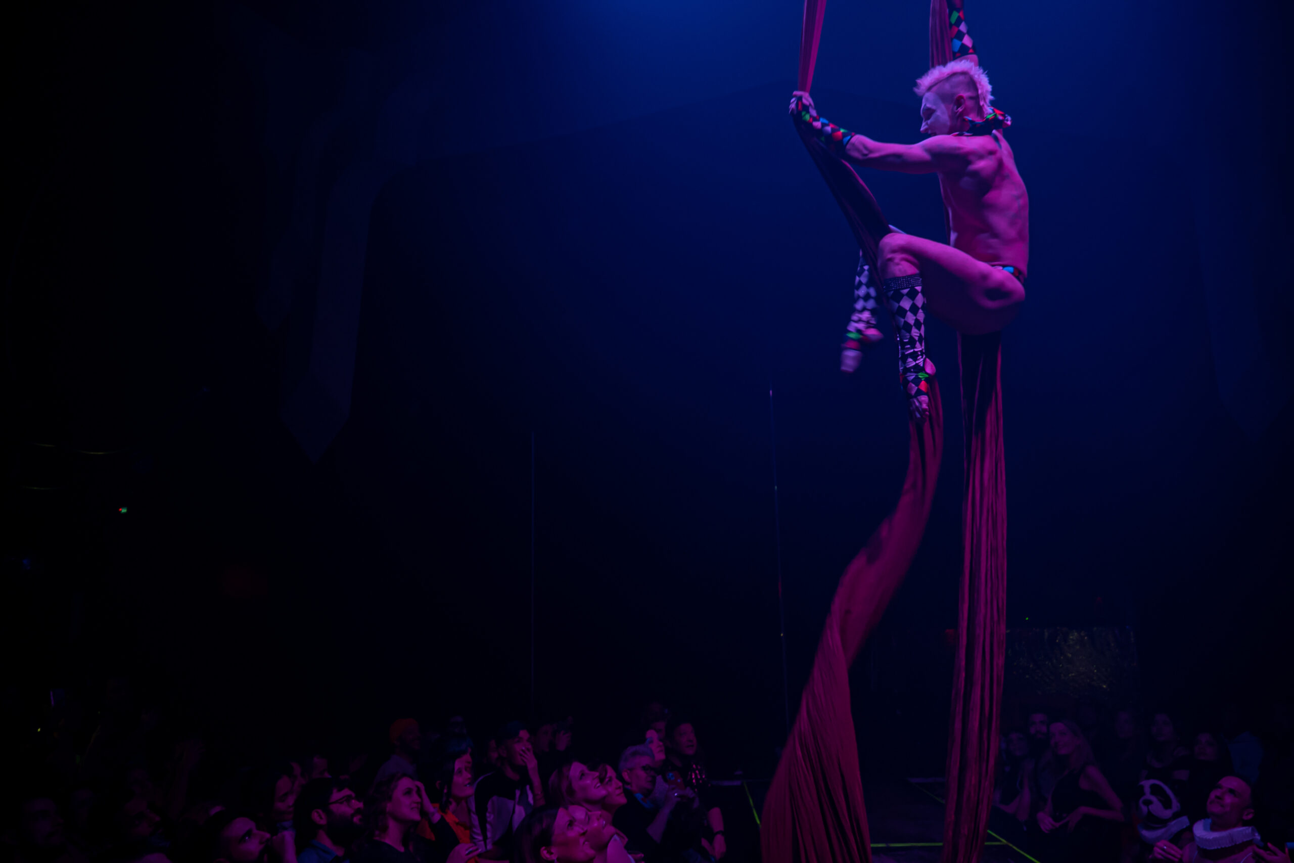 Silks perfomer hanging above crowd.